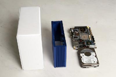 写真の白い箱が、世界最小を目指して開発中のMini-ITXシステム。内蔵電源ユニットは2.5インチHDDを2つ重ねたものより若干大きい程度